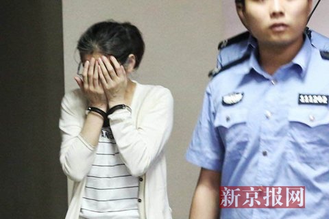犯罪嫌疑人庞建贞双手捂脸，被法警带着准备进入法庭。新京报记者尹亚飞摄