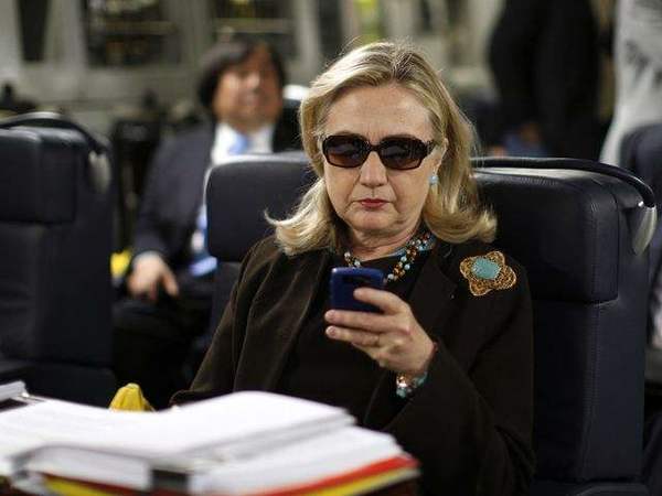  2011年10月18日，美国国务卿希拉里在飞往利比亚首都的黎波里的军用运输机上查看手机信息。（图片来源：新华/美联）