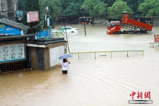 6月19日，江西省景德镇市遭遇暴雨袭击，导致城区部分小区和道路积水严重，市民出行不便。图为市民冒雨在江西省景德镇市朝阳路积水路段涉水出行。