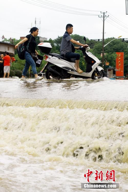 6月19日，江西省景德镇市遭遇暴雨袭击，导致城区部分小区和道路积水严重，市民出行不便。图为市民冒雨在江西省景德镇市珠山区新厂街道景华小区积水路段涉水出行。