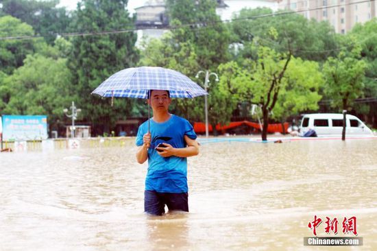 6月19日，江西省景德镇市遭遇暴雨袭击，导致城区部分小区和道路积水严重，市民出行不便。图为市民在江西省景德镇市朝阳路积水路段涉水出行。