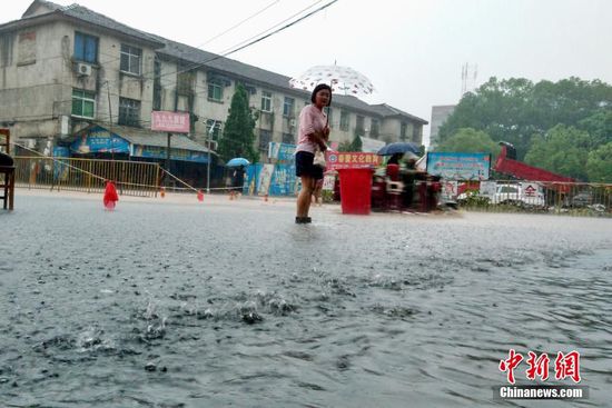 6月19日，江西省景德镇市遭遇暴雨袭击，导致城区部分小区和道路积水严重，市民出行不便。图为市民冒雨在江西省景德镇市朝阳路积水路段涉水出行。