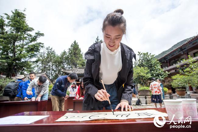 7月25日，车队来到丽江东巴文化研究所，体验东巴传统文化。图为活动参与者尝试书写象形文字。 