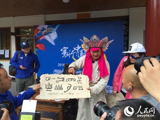 7月25日，车队来到丽江东巴文化研究所，体验东巴传统文化。图为一名东巴向活动参与者展示东巴文字。 