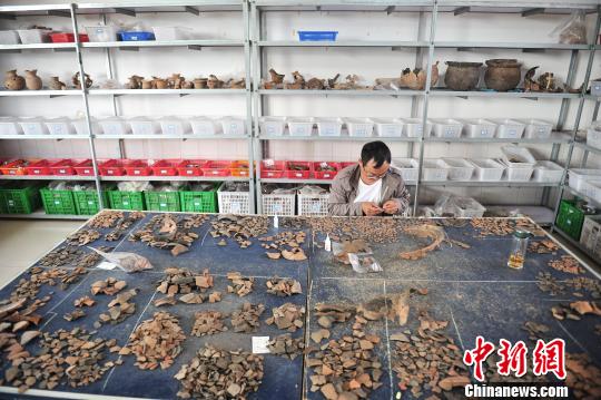 图为工作人员对出土的陶器碎片进行修复刘冉阳摄