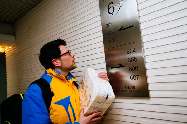 资料图：来自英国的“洋快递”何文旭查看楼牌，核对送货地址。新华社记者刘金海摄