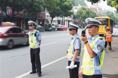 2015年7月17日，浙江桐庐，桐庐县城区中队交警、辅警手持抓拍设备在斑马线区域查处“车不让人”现象。图/视觉中国