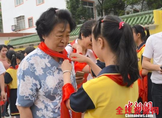 图为“临川八一希望小学”少先队员给贺晓明戴红领巾。 钟欣摄