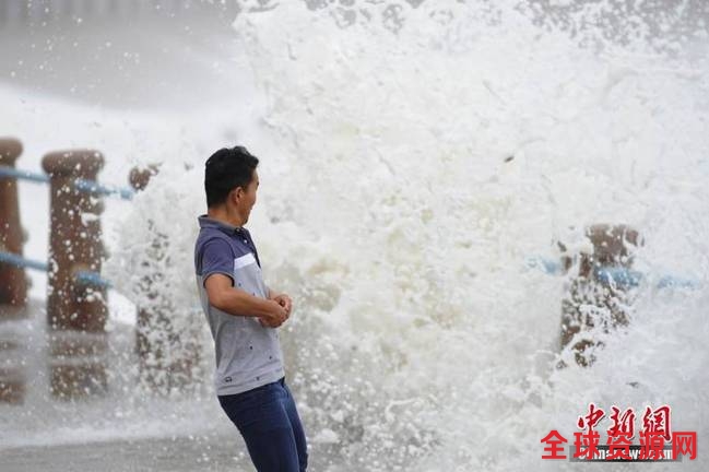 一名游客在青岛市澳门路冒险拍摄海潮。