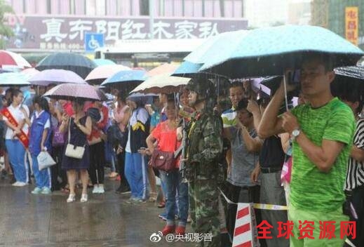 执勤期间，忽降大雨，正在考场外等待的家长为执勤官兵撑伞。