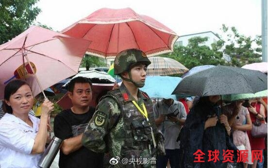 执勤期间，忽降大雨，正在考场外等待的家长为执勤官兵撑伞。