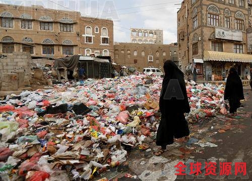图为5月8日，在也门萨那，几名妇女走过街头堆积的垃圾袋。（新华社/路透）