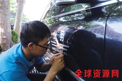  6月8日下午，山东济南，工作人员正在对公务用车进行标识化喷涂工作。 陈玮 摄