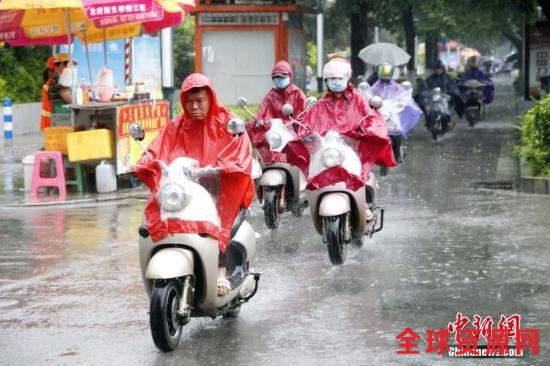 6月16日，广西柳州市遭暴雨侵袭，民众穿着雨衣骑电动车出行。 中新社记者 朱柳融 摄