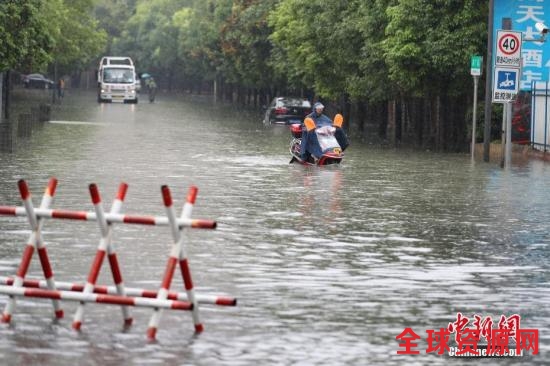 资料图：6月12日，贵阳市民骑电动车在积水路段行驶。中新社记者 贺俊怡 摄