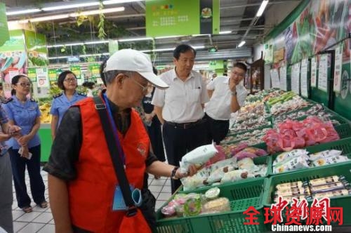 图为食品安全义工队员在超市对食品的生产日期进行检查 问泽英 摄