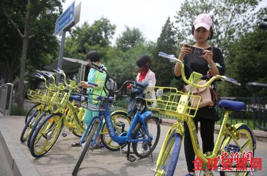 资料图 6月8日，民众在北京街头扫码租用一款“土豪金”色的共享单车。 中新社记者 杨可佳 摄