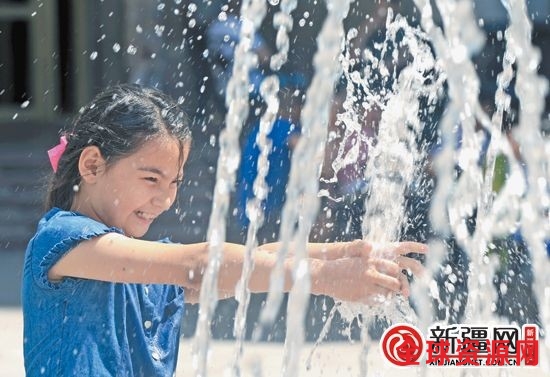 13日，在黄河路，9岁的帕孜拉·阿布都克尤木在喷泉旁玩耍。（本报全媒体记者张利民摄）