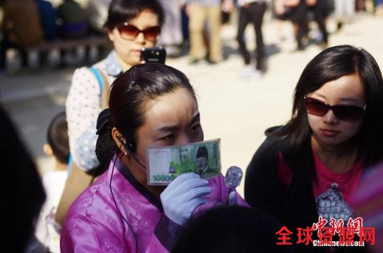 资料图：韩国首尔景福宫内一位汉语导游正向中国游客介绍韩文的由来。 中新社发 贾天勇 摄