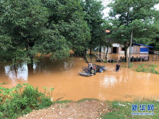 7月24日，在老挝阿速坡，居民在被洪水淹没的区域涉水出行。