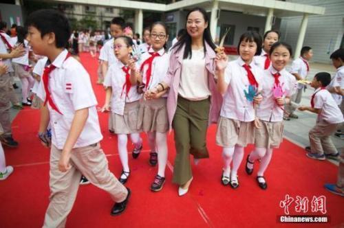 资料图：教师节，老师们牵着学生的手走过红地毯步入校园。张云摄