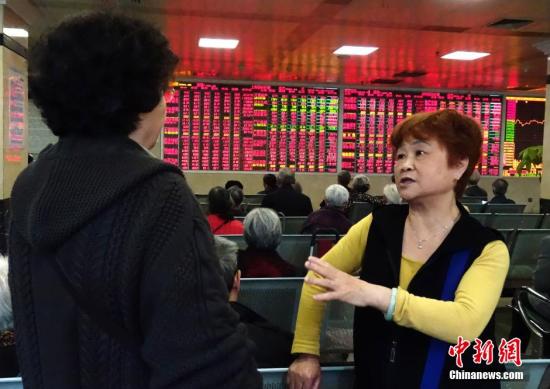 资料图：两位股民正讨论股市走势。中新社记者 刘忠俊 摄