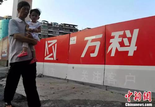 资料图:福州民众从万科楼盘工地旁经过。中新社记者 张斌 摄 资料图:福州民众从万科楼盘工地旁经过。中新社记者 张斌 摄