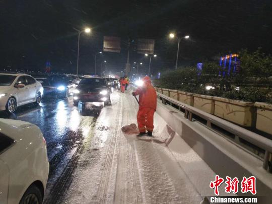 30日晚的降雪恰逢城市交通晚高峰，南京环卫工人在街头人工扫雪。南京城管