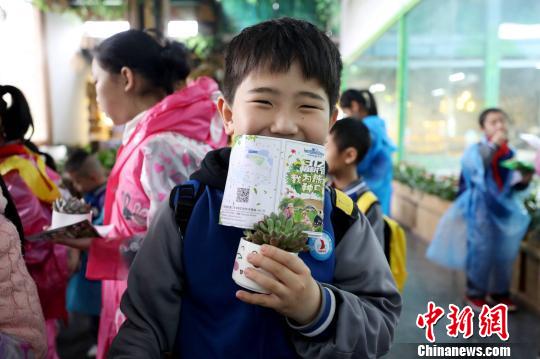 参加植树活动的小朋友获赠“植树节纪念证书”和一盆多肉植物，开心不已。 供图 摄