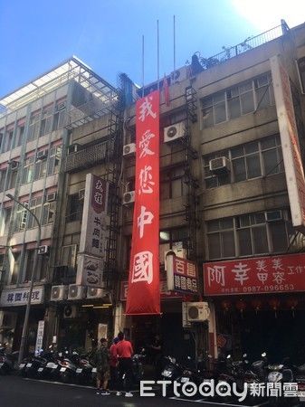 10月1日，“爱国同心会”成员在楼顶挂“我爱您中国”红色条幅。来源：台湾“东森新闻云”