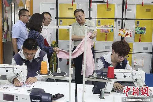 5月9日，北京劳动保障职业学院面向大众举办校园开放日活动，通过“特色课程展示”、“社团活动展示” 、“校园参观”等活动，全方位地展现高端技术技能人才贯通培养。该学院今年高端贯通项目的5个专业方向分别为人力资源管理 、社会保障、智慧养老与健康管理、智慧城市设施安全管理、智能楼宇信息技术，需要进行七年贯通培养，包括两年基础教育阶段与北京十一学校联手全面实施选课走班，三年专业教育阶段学生接受本院职业教育，最后两年的本科教育阶段由北京信息科技大学、首都经济贸易大学和首都医科大学等进行本科阶段培养。图为北京劳动保障职业学院院长李继延(右二)在开放日活动中介绍学院特色专业。 中新社记者 盛佳鹏 摄