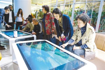 在辽宁省大连市某购物中心的“沉浸式数字旅游体验中心”，人们在体验AI智能触控台等旅游新产品。人民视觉