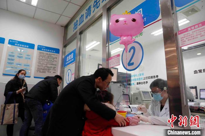 家长带着孩子在上海儿童医院急诊化验科进行检查。 殷立勤 摄