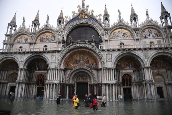  11月13日，人们穿过圣马可大教堂，穿过洪水泛滥的圣马可广场。 图片来源：MARCO BERTORELLO / AFP / AFP via Getty Images