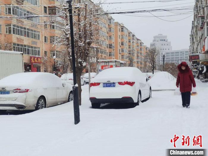 行人戴着口罩在雪地里行走。 姜辉 摄