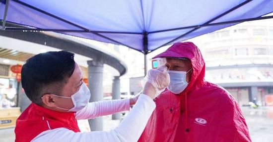志愿者在为居民测体温（图片来源：新华网 肖和勇摄）