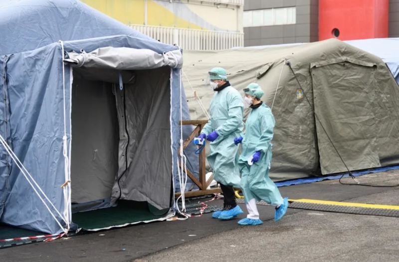 3月3日，在意大利布雷西亚，医务人员进入在医院外搭建的帐篷。新华社发