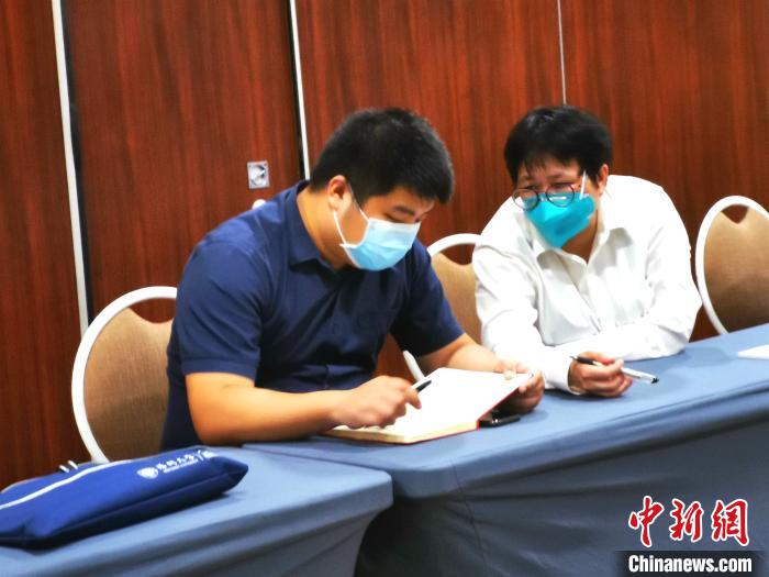4月6日，在菲中国留学生医学翻译志愿者(左)在配合中国抗疫医疗专家组成员与菲中华崇仁医院座谈。 关向东 摄