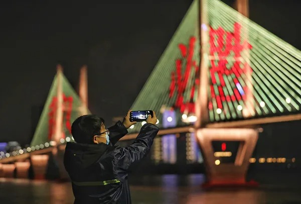 2月28日，武汉长江二桥打出“武汉必胜”字样。灯光维修师温瑞在雨夜中拍照记录。新华社发