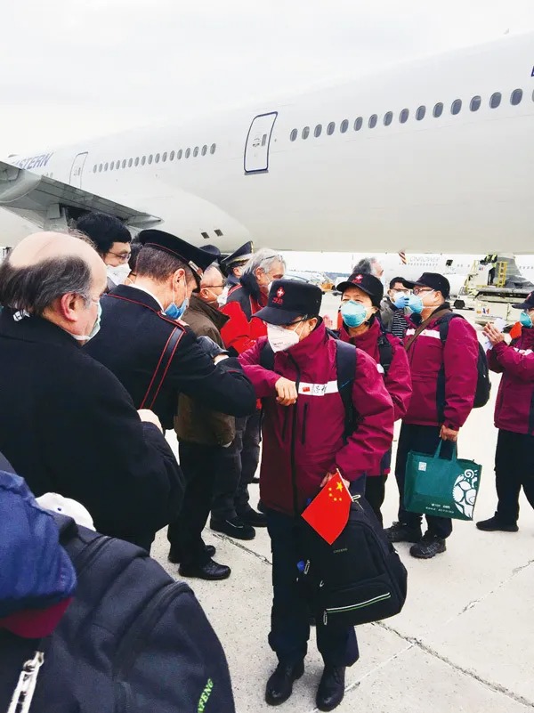 2020年3月25日，在意大利米兰马尔奔萨机场，意方人员以“击肘”的方式欢迎中国第三批赴意大利抗疫医疗专家组成员的到来。