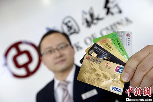 资料图：山西太原的银行工作人员展示各类信用卡。 中新社记者 张云 摄